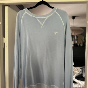 Ljusblå tröja från GANT - Säljer en snygg ljusblå tröja från GANT i storlek M. Den har långa ärmar och är perfekt för en avslappnad stil. Tröjan är i bra skick och har en liten GANT-logga på bröstet. Perfekt för vår och sommar!