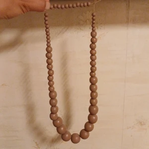 Halsband med träpärlor - Mellanstor halsband. Köpt i Finland. Aldrig använd. Gummibandet kan ersättas om ni önskar mot en transparent band istället.