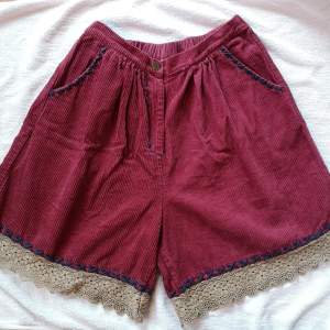 Unika vinröda manchester shorts med snygga spetsdetaljer i beige längs nederkanten och mörkblåa broderade detaljer vid fickorna & längs benen. ENDAST TESTADE. Baksidan har inga fickor. Ord pris 412kr. ***Köpare står för frakt om inget annat anges!