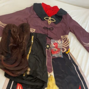 Hu Tao Cosplay - Endast använd 1 gång så den är i toppen skick. Storlek S, peruken är ostylad, inte klippt och har inte hårsprej i sig. Strumpor inkluderas inte och en foot ring saknas.