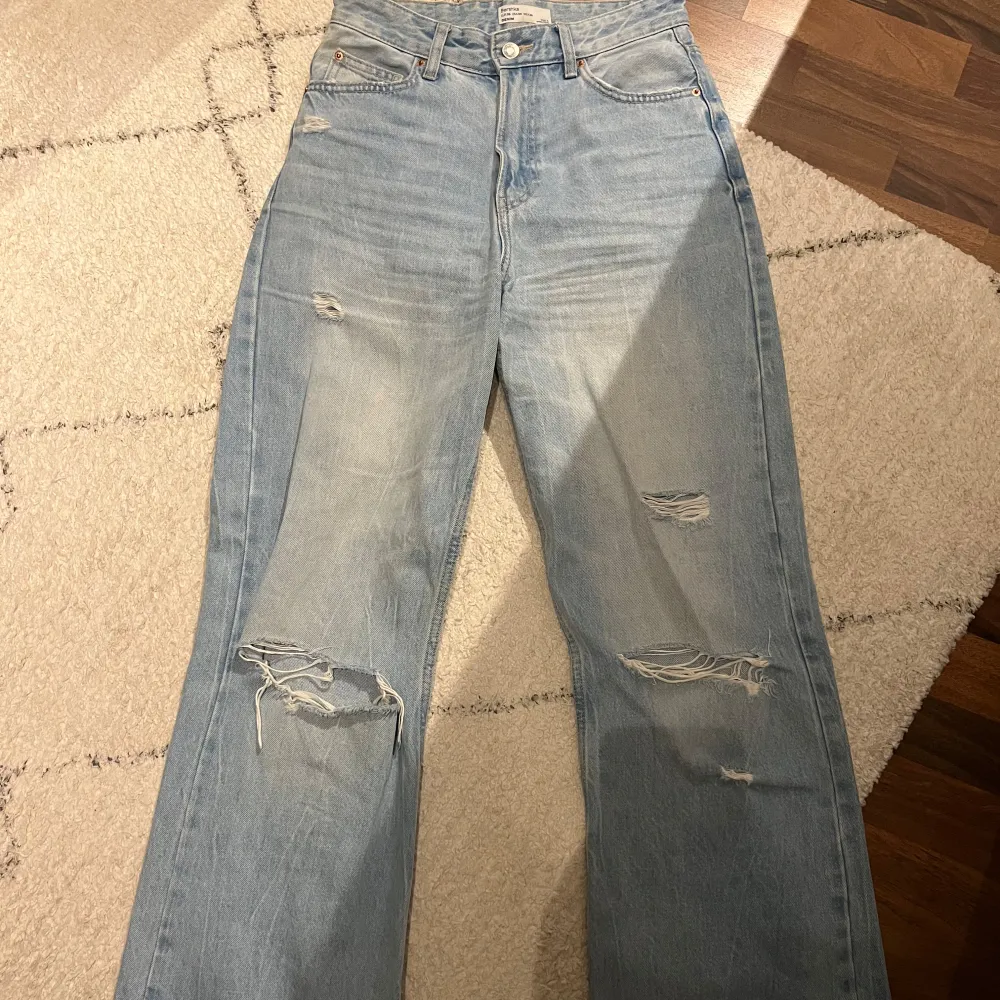 Säljer ett par ljusa jeans i mycket bra skick. De är högmidjade och har en straight passform med coola slitningar på framsidan och lite på baksidan. Perfekta för en avslappnad stil och kan matchas med nästan vad som helst🌸💕. Jeans & Byxor.