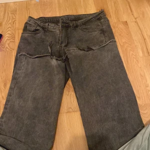Grå jeans från Shein - Säljer ett par grå jeans från Shein i storlek S. De har en cool, sliten look med revor på benen. Perfekta för en avslappnad stil. Materialet är en blandning av bomull och polyester, vilket gör dem både bekväma och hållbara.