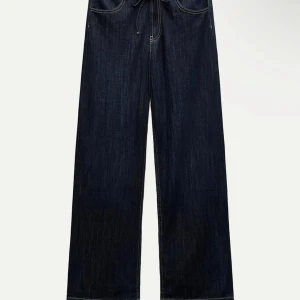 Mörkblå jeansbyxor - Säljer ett par snygga mörkblå jeansbyxor i mycket bra skick. De har en klassisk design med dragkedja och knapp framtill. Byxorna har en loose passform och raka ben, vilket ger en avslappnad stil. Perfekta för både vardag och fest!