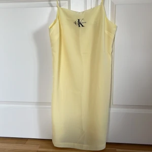 Gul klänning från Calvin Klein Jeans - Säljer en superfin gul klänning från Calvin Klein Jeans i storlek M. Den har justerbara band och har en enkel, stilren design. Perfekt för sommardagar eller en avslappnad fest. Klänningen är i mycket bra skick och redo för nya äventyr! 🌼