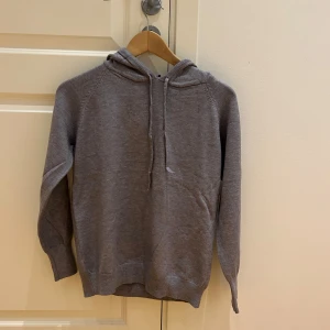 Grå stickad hoodie  - Säljer en stilren grå hoodie i merinoull. Tröjan är aldrig använd utan bara testad. Säljer den då den inte passade mig. Passar till allt och är superbekväm! 