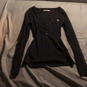 Svart Abercrombie and fitch tröja  - Höstig Abercrombie and fitch tröja som är svart med 7 knappar i fram, loggan in broderad i fram. Storlek M och är i bra skick, säljer eftersom jag har tröttnat lite på den. Köpte den för ish 1 - 1 1/2 år sedan. 