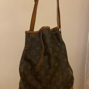 Louis Vuitton Noé  - Säljer en klassisk Louis Vuitton axelväska med monogrammönster i modellen Noé. Den är i acceptabelt skick med synligt slitage på kanterna i botten som har blivit med åldern. Men den är fortfarande stilren och rymlig. Insidan är fräsch och ren. Kvitto från Luxe Porter finns. Fler bilder/filmklipp går att få. Pris går att diskutera vid snabb och smidig affär. 