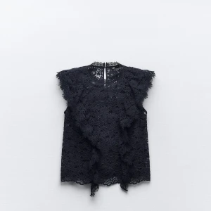 Svart spetsblus - Säljer en elegant marinblå spetsblus med vackra volangdetaljer. Den är ärmlös och perfekt för en festlig kväll. Blusen har en fin struktur och ger en lyxig känsla.🩵