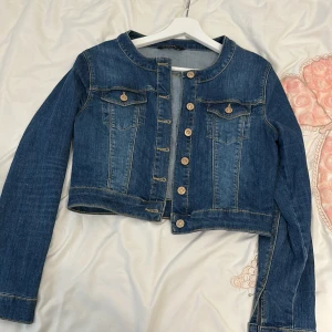 Blå jeansjacka från LCW Jeans - Säljer en snygg blå jeansjacka från LCW Jeans. Den är croppad och har långa ärmar med knappar framtill. Perfekt för en casual look och passar bra till både vår och höst. Jackan har två bröstfickor med knappdetaljer.