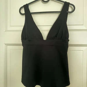 Svart fest topp med knyt i ryggen Nelly - En svart topp perfekt till fest med knyt i ryggen. Den är aldrig använd, endast tvättad en gång och säljer då den aldrig kom till användning