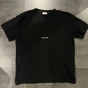 Saint Laurent t-shirt - Jag säljer nu denna snygga t-shirt. Det är en saint Laurent t-shirt som är andvänd sparsamt och är i ett väldigt bra skick.  Priset är inte hugget i sten och med mer frågor så skriv bara!🙌🤝
