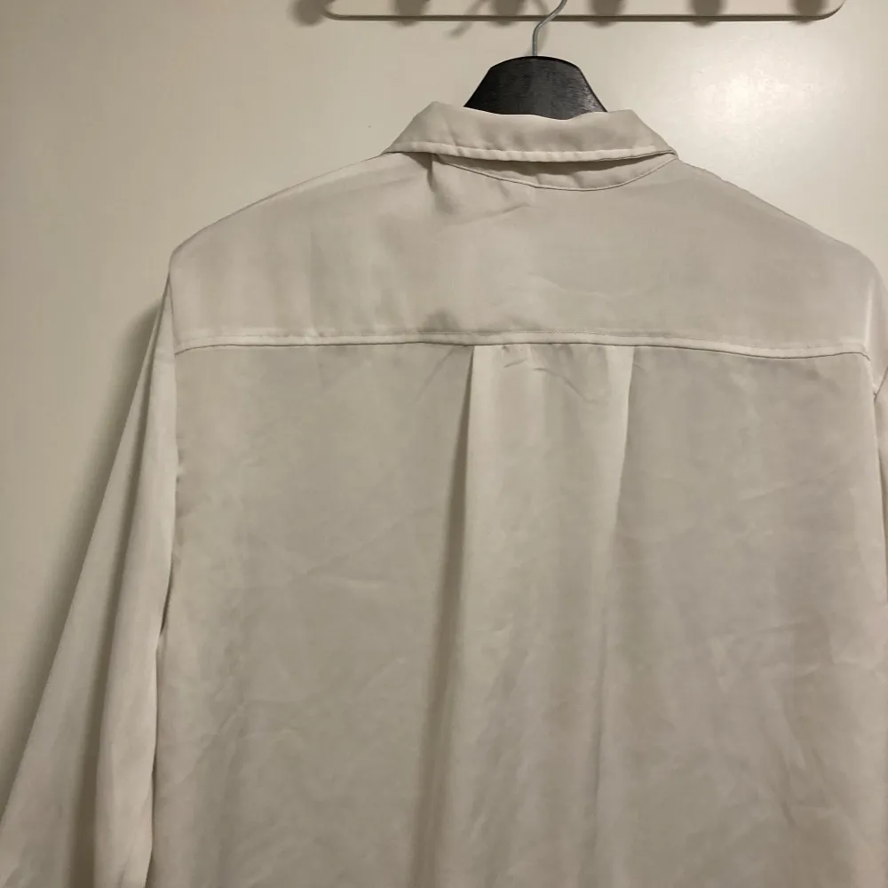 Säljer en klassisk vit långärmad skjorta. Skjortan har en stilren design med knappar framtill och vid ärmsluten. Perfekt för både formella och avslappnade tillfällen. Den är redo att bäras till nästa event! Aningen urtvättad annars fin. Paidat.