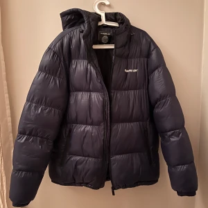 Svart pufferjacka från Closure LDN - Säljer en snygg och varm svart pufferjacka från Closure LDN. Jackan har en dragkedja framtill och är perfekt för kyliga dagar. Den är i ny skick då jag inte använt den så speciellt mycket. Passar mig som är 190 och väger 80kg. Priset kan diskuteras.