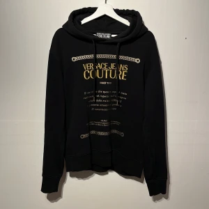Versace hoodie - Hej! Säljer denna sjukt snygga versace Jeans couture hoodien! Riktigt snyggt tryck och text i guld! Väldigt skön hoodie i bra skick utan defekter🙌självklart äkta och finns äkthets kod på bild 5😊nypris 3000kr mitt pris 1199kr! Skriv vid intresse // DC