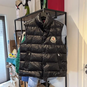 Moncler Tib väst - Moncler tib väst av den äldre modellen med stor logga, saknar cartoon och ett litet hål på insidan annars nyskick. Storlek 2 passar M, nypris 11.000 mitt pris 3200 men tar emot rimliga bud! Över 80 refs finns från nöjda kunder!