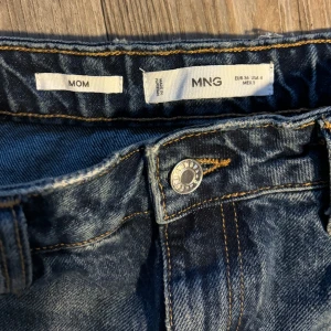 Blå mom jeans från MNG/ Mango  - Säljer ett par snygga blå mom jeans från MNG. Knappt använda och inköpta augusti 2024❣️  De har en klassisk femficksdesign och är tillverkade i slitstarkt denim. Perfekta för en avslappnad vardagslook. Passar bra till både sneakers och boots!