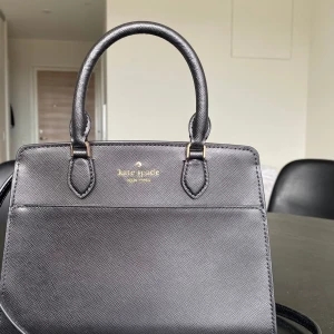 Kate Spade svart handväska - helt oanvänd - Fick den här väskan för ett par månader sen men inte använt den alls & kommer tyvärr inte det.  Den är med andra ord helt ny (med plast kvar på dragkedjorna) och storleken är perfekt. Utgångspris: 420 pund (ca 5100kr). Kostar nu runt 1900kr 