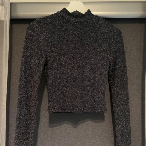 Topp - Kort glittrig polotopp med öppen rygg. Storlek XS. Använd ett fåtal gånger.