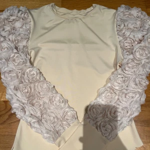 Ljusrosa/beige tröja med Blom armar - Säljer min systers tröja. Inga synliga defekter förutom att den är av klippt där nere (om man vill kan man fixa det och klippa rakare.) den är i storlek S men den är väldigt stretchig så den passar även M