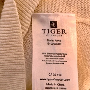 Beige tröja från Tiger of Sweden - Säljer en helt ny elegant beige tröja från Tiger of Sweden, modell Annie. Den är tillverkad i en lyxig blandning av siden och bomull, vilket gör den både mjuk och bekväm. Tröjan har en stilren v-ringning och långa ärmar, perfekt för både vardag och fest. Ett måste i garderoben för den stilmedvetna!