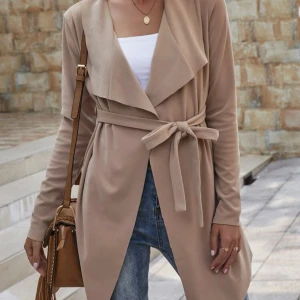 Beige kavaj från Shein - Säljer en snygg beige trenchcoat från Shein. Den har en stilren design med långa ärmar och en öppen front utan knappar. Perfekt för både vardag och fest! Materialet är tunt, mjukt och bekvämt.