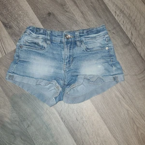 Blå jeansshorts från LAB Industries  - Snygga blå jeansshorts från LAB Industries med en klassisk femficksdesign och knappgylf. De har en lätt slitning för en avslappnad look och uppvikta kanter. Perfekta för varma sommardagar! Dom har också en liten fläck som ni kan se på en av bilderna