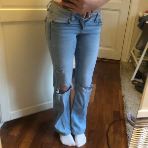 Ljusblå bootcut jeans med slitningar - Snygga ljusblå jeans i bootcut-stil med coola slitningar på knäna. De har en klassisk femficksdesign och knappar bak. Perfekta för en avslappnad look. Jag är 161!