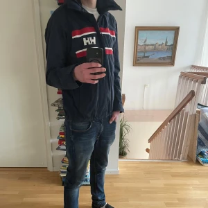 Helly Hansen Jacka - As fet helly Hansen seglarjacka i jätte bra skick, as skön till svala sommarkvällar och våren!!  Jag är 187 och väger 73 och den sitter bra. Justerbar midja, vid bilden är den väldigt tajt i midjan.                                       Hör av er vid fler frågor!