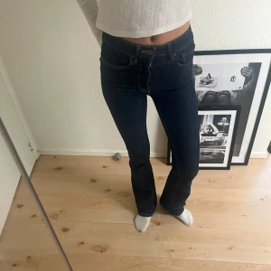 Mörkblå jeans med bootcut - Snygga mörkblå jeans med bootcut-stil och låg midja. Klassisk design med fem fickor och knappgylf. Perfekta för en avslappnad look. Slutsålda!