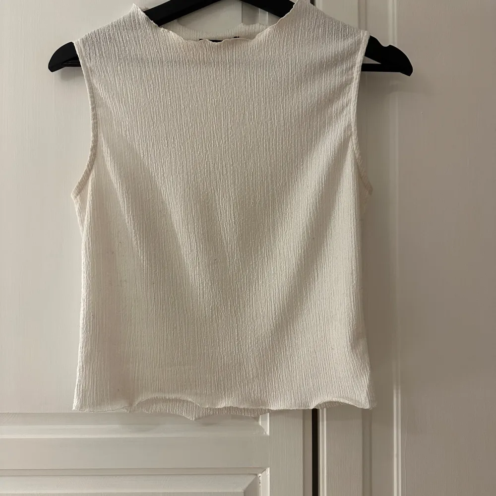 Säljer en stilren vit ärmlös topp från Missay. Toppen har en ribbad textur och en enkel design som passar perfekt till olika outfits. Perfekt för varma dagar eller som ett lager under en jacka.. Yläosat.