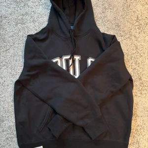 Svart hoodie med tryck - Säljer en svart hoodie med stort tryck på framsidan. Storlek L. Skriv om du är intresserad!!