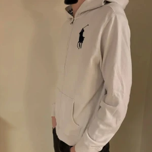 Vit hoodie från Ralph Lauren - Xl barn passar S tar gärna byten Säljer en stilren vit hoodie från Ralph Lauren med dragkedja och det klassiska logotypbroderiet på bröstet. Tröjan har långa ärmar och en bekväm passform. Perfekt för en avslappnad look.