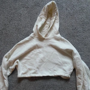 Vit croppad hoodie - Säljer en vit croppad hoodie ifrån ellos! Skulle säga att storleken är ungefär 11-12!