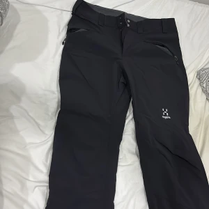 Svarta täckbyxor från Haglöfs - Säljer ett par svarta täckbyxor från Haglöfs. Byxorna har dragkedjor vid fickorna och en bekväm passform, perfekt för kalla dagar. De är designade för att hålla dig varm och torr under vinterns äventyr.
