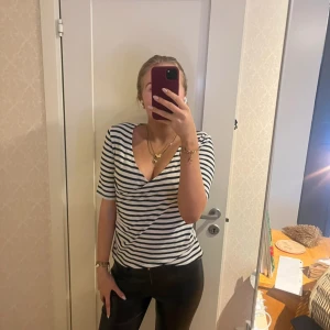 Randig v-ringad topp - Säljer en stilren randig topp med v-ringning. Toppen har korta ärmar och ett blåvitt mönster. Omlott topp ifråm bondelid i storlek i 36.