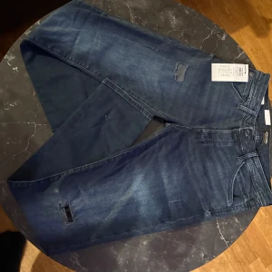 Blå jeans från Jack & Jones - Helt nya snygga blå jeans från Jack & Jones med slitna detaljer för en trendig look. De har en klassisk femficksdesign och en bekväm passform. Perfekta för en avslappnad stil. För fler bilder är det bara och skriva!