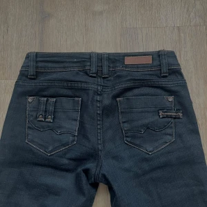 Svarta bootcut jeans - Snygga svarta bootcut jeans med låg midja och klassiska femficksdetaljer. Jeansen har en stilren design med coola detaljer på fickor. Passar perfekt för alla tillfällen. Har inga bilder på då de inte passar. Skriv gärna om ni vill ha fler bilder eller så🥰pris kan diskuteras! Midjemått tvärs över:34cm Innerbensmått:83cm