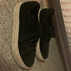 Svarta sneakers från Vagabond - Snygga svarta mocka sneakers från Vagabond med vit sula. Skorna har snörning och en stilren design som passar perfekt till vardags. De är i storlek 39 och har en bekväm passform. Skorna har en liten skada på insidan av foten annars som nya! Ny pris 1300