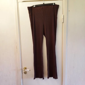 Bruna ribbade flare byxor - Snygga bruna byxor med ribbad textur och hög midja. Från H&M i st XL. De har en bootcut-stil som ger en trendig look. Perfekta för en avslappnad stil med en touch av elegans. Något noppriga därav de låga priset.