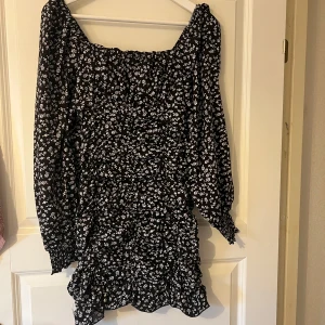 Svart blommig klänning - Säljer en söt svart klänning med vita blommor och detaljer. Storlek XS. 50kr + frakt