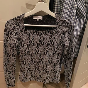 Svart spetsblus från Anne Fontaine - Elegant svart blus från Anne Fontaine med vackert vitt spetsmönster. Blusen har långa ärmar och en stilren design som passar perfekt för speciella tillfällen. 💗