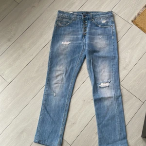 Ljusblå jeans från Dondup midja 41, längd 95 - Snygga ljusblå jeans från Dondup i en limited edition. De har en straight fit med slitna detaljer och knappar framtill. Perfekta för en avslappnad stil.