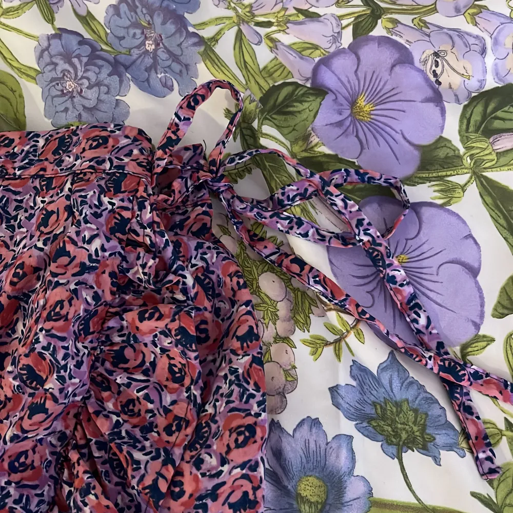 Säljer en söt blommig kjol i rosa och blått med volangdetaljer. Kjolen har en omlott-design och knytband i midjan för justerbar passform. Perfekt för sommarens varma dagar!. Hameet.