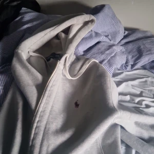 Ralph lauren hoddie med luva och dragkedja bra skick använt i ungefär 3 månader  - Säljer en stilren grå hoodie från Ralph Lauren med dragkedja och den klassiska loggan på bröstet. Perfekt för en avslappnad look. 🐎