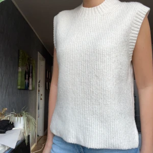 Vit ärmlös stickad topp - Säljer en knappt använd vit ärmlös stickad topp. Perfekt för lager-på-lager eller att bära som den är. Den har en ribbad struktur som passar bra till både jeans och kjol.