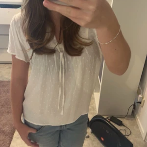 Vit blus med knytband - Säljer en söt vit blus som har ett diskret prickigt mönster och som är perfekt för både vardag och fest. Den är luftig och bekväm vilket passar mest för vår och sommar. Kontakta mig vid frågor💕