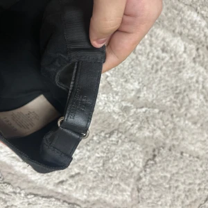 Svart keps med monogrammönster - Säljer en snygg svart keps från Gucci med deras ikoniska monogrammönster. Kepsen har en justerbar rem baktill och detaljer i rött och grönt på sidan. Perfekt för att ge din outfit en lyxig touch!