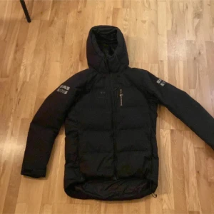 Svart dunjacka från Sail Racing - Nypris 4200kr. Säljer en svart dunjacka från Sail Racing i mycket bra skick. Den har en praktisk dragkedja och en mysig huva för extra värme. Perfekt för kalla vinterdagar och höstpromenader. Jackan är långärmad och har en stilren design. Passar både till vardags och utomhusaktiviteter. Den är i strl M men passar även folk som har strl L