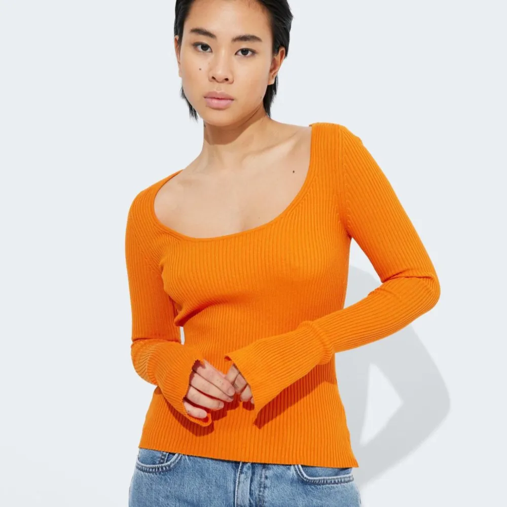 Säljer en snygg orange ribbad tröja med lång ärm och en djup, fyrkantig urringning. Perfekt för höst och vår, den är både stilren och bekväm. Passar bra till jeans för en casual look. 🧡. Toppar.