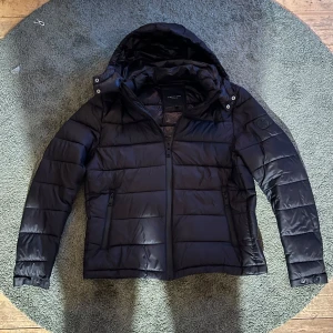 Svart pufferjacka från Polo Club - Säljer en snygg svart pufferjacka från Polo Club i storlek L. Jackan har en dragkedja framtill och en mysig huva. Perfekt för kyliga höst- och vinterdagar. Den är i mycket bra skick, bara andvänd i en vinter mvh Tim 